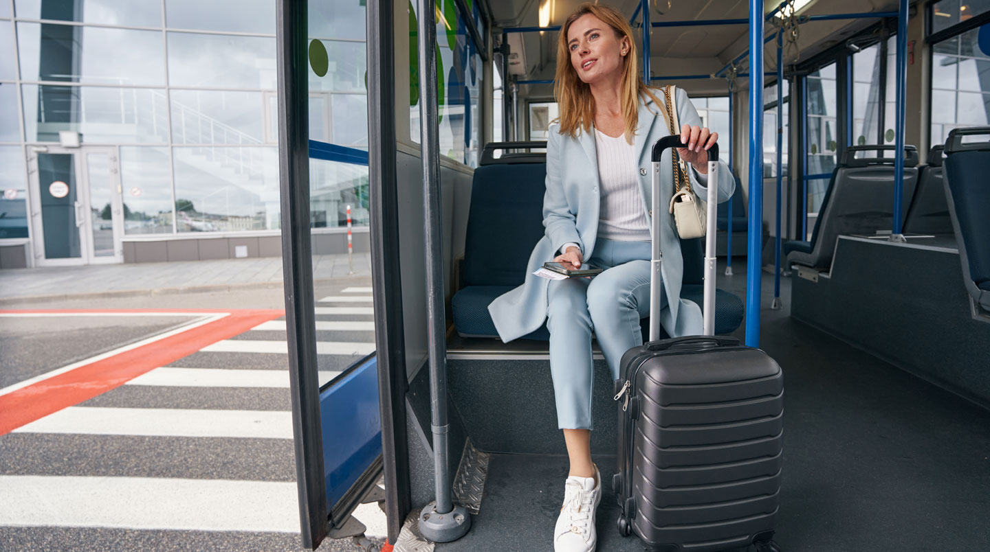 Passagers montant dans une navette climatisée blanche devant un parking sécurisé à Roissy